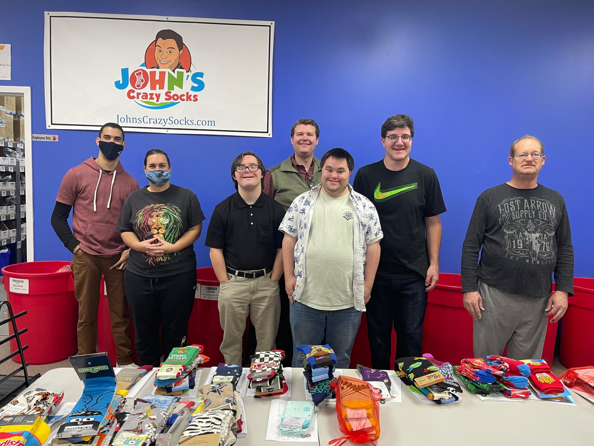 John Cronin, co-founder of John's Crazy Socks with the JCS staff smiling for the camera.