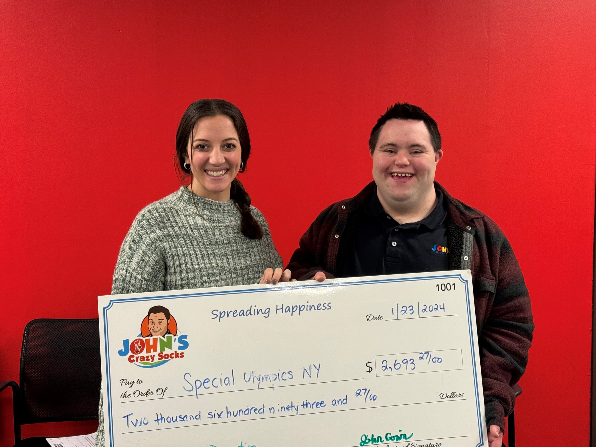 John Cronin of John’s Crazy Socks proudly presents a donation check for $2,693.27 to Special Olympics NY, showcasing the company’s commitment to giving back and supporting inclusion.