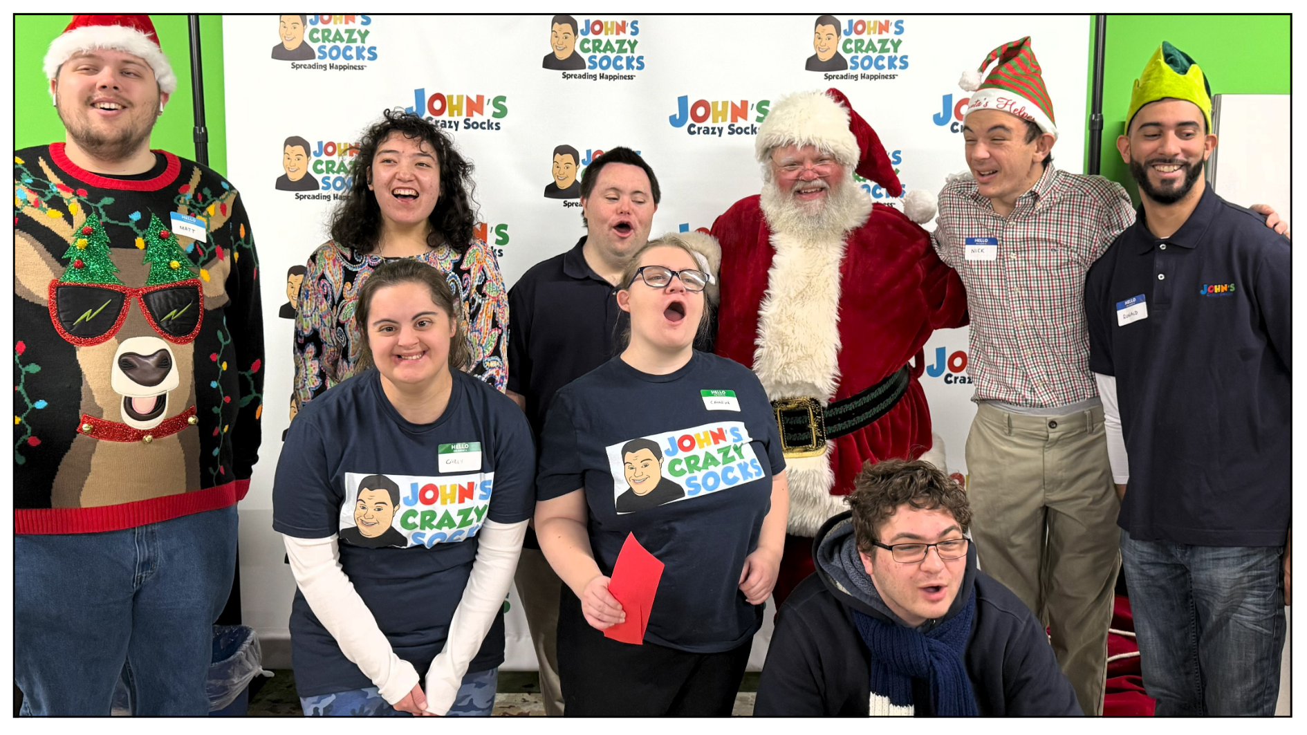 A festive group photo of the John’s Crazy Socks team with Santa, celebrating the holidays with smiles and cheer.